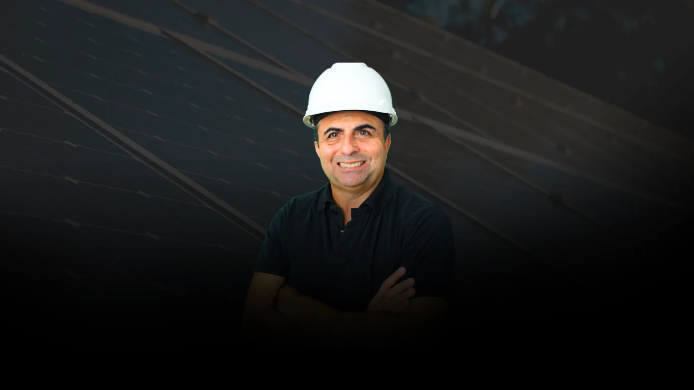 Vanísio Pinheiro com capacete de obra em frente a painéis solares